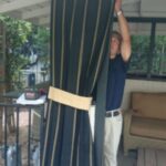a man installing black drapes - custom awnings - custom awnings near me - custom awnings for decks - custom awnings for business - custom door awnings near me - spear awnings - aluminum awnings - dome awnings