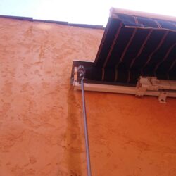 stripe awning installed on an orange house - custom awnings - custom awnings near me - custom awnings for decks - custom awnings for business - custom door awnings near me - spear awnings - aluminum awnings - dome awnings