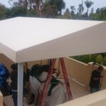 men installing a white cabana on a balcony - custom awnings - custom awnings near me - custom awnings for decks - custom awnings for business - custom door awnings near me - spear awnings - aluminum awnings - dome awnings