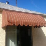 yellow house with stripe dome awning for windows - custom awnings - custom awnings near me - custom awnings for decks - custom awnings for business - custom door awnings near me - spear awnings - aluminum awnings - dome awnings