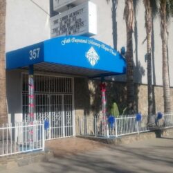 white building with railings and a blue entrance canopy - custom awnings - custom awnings near me - custom awnings for decks - custom awnings for business - custom door awnings near me - spear awnings - aluminum awnings - dome awnings