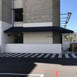 grey building with black awning - custom awnings - custom awnings near me - custom awnings for decks - custom awnings for business - custom door awnings near me - spear awnings - aluminum awnings - dome awnings