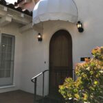 white house with white dome awning for its wooden door - custom awnings - custom awnings near me - custom awnings for decks - custom awnings for business - custom door awnings near me - spear awnings - aluminum awnings - dome awnings