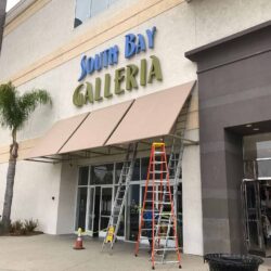South Bay Galleria with light brown awnings and ladders on the entrance - custom awnings - custom awnings near me - custom awnings for decks - custom awnings for business - custom door awnings near me - spear awnings - aluminum awnings - dome awnings