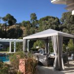 poolside corner with sofas and white cabana and trees in the background - custom awnings - custom awnings near me - custom awnings for decks - custom awnings for business - custom door awnings near me - spear awnings - aluminum awnings - dome awnings