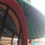 yellow store with green dome awnings - custom awnings - custom awnings near me - custom awnings for decks - custom awnings for business - custom door awnings near me - spear awnings - aluminum awnings - dome awnings