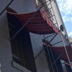 grey building with red spear awnings for windows - custom awnings - custom awnings near me - custom awnings for decks - custom awnings for business - custom door awnings near me - spear awnings - aluminum awnings - dome awnings