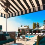 poolside with two stripe cabanas with trees in the background - custom awnings - custom awnings near me - custom awnings for decks - custom awnings for business - custom door awnings near me - spear awnings - aluminum awnings - dome awnings