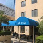 a yellow building with a blue entrance canopy - custom awnings - custom awnings near me - custom awnings for decks - custom awnings for business - custom door awnings near me - spear awnings - aluminum awnings - dome awnings
