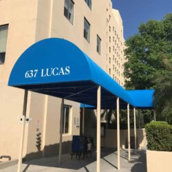 a yellow building with a blue entrance canopy - custom awnings - custom awnings near me - custom awnings for decks - custom awnings for business - custom door awnings near me - spear awnings - aluminum awnings - dome awnings