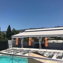 poolside with grey cabana and orange folding umbrellas - custom awnings - custom awnings near me - custom awnings for decks - custom awnings for business - custom door awnings near me - spear awnings - aluminum awnings - dome awnings