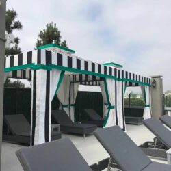 poolside with two stripe cabanas with trees in the background - custom awnings - custom awnings near me - custom awnings for decks - custom awnings for business - custom door awnings near me - spear awnings - aluminum awnings - dome awnings