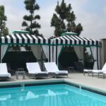 poolside with two stripe cabanas with trees in the background - custom awnings - custom awnings near me - custom awnings for decks - custom awnings for business - custom door awnings near me - spear awnings - aluminum awnings - dome awnings