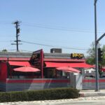 restaurant with red awnings and red folding umbrella for outdoor seating - custom awnings - custom awnings near me - custom awnings for decks - custom awnings for business - custom door awnings near me - spear awnings - aluminum awnings - dome awnings