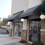 store protected by CCTV with grey store front awnings - custom awnings - custom awnings near me - custom awnings for decks - custom awnings for business - custom door awnings near me - spear awnings - aluminum awnings - dome awnings