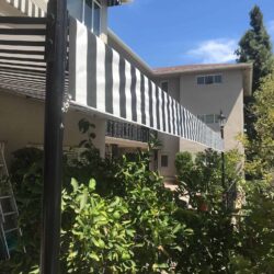 a house with a garden and stripe awnings - custom awnings - custom awnings near me - custom awnings for decks - custom awnings for business - custom door awnings near me - spear awnings - aluminum awnings - dome awnings