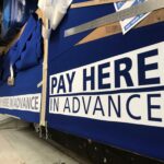 "pay here in advance" sign laid on a table - custom awnings - custom awnings near me - custom awnings for decks - custom awnings for business - custom door awnings near me - spear awnings - aluminum awnings - dome awnings