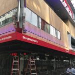 orange building with different restaurants with red awning for its entrance - custom awnings - custom awnings near me - custom awnings for decks - custom awnings for business - custom door awnings near me - spear awnings - aluminum awnings - dome awnings