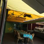 restaurant with yellow storefront awning with empty tables and chairs - custom awnings - custom awnings near me - custom awnings for decks - custom awnings for business - custom door awnings near me - spear awnings - aluminum awnings - dome awnings