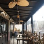 closed restaurant with awnings and drapes for its balcony seating with tables and chairs - custom awnings - custom awnings near me - custom awnings for decks - custom awnings for business - custom door awnings near me - spear awnings - aluminum awnings - dome awnings