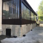restaurant with brown awnings and drapes with plants decoration - custom awnings - custom awnings near me - custom awnings for decks - custom awnings for business - custom door awnings near me - spear awnings - aluminum awnings - dome awnings