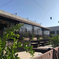 restaurant with brown awnings and drapes with plants decoration - custom awnings - custom awnings near me - custom awnings for decks - custom awnings for business - custom door awnings near me - spear awnings - aluminum awnings - dome awnings