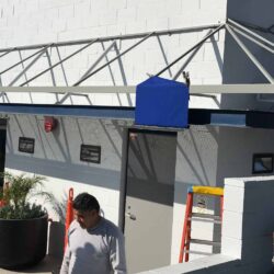 blue awnings being installed on a white building - custom awnings - custom awnings near me - custom awnings for decks - custom awnings for business - custom door awnings near me - spear awnings - aluminum awnings - dome awnings