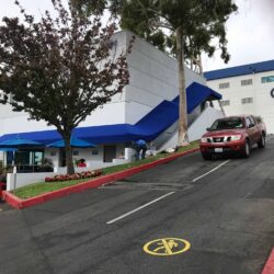 a white building with blue awnings with a car passing by - custom awnings - custom awnings near me - custom awnings for decks - custom awnings for business - custom door awnings near me - spear awnings - aluminum awnings - dome awnings
