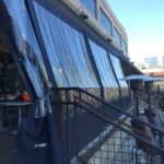 restaurant with black drapes for its balcony seating - custom awnings - custom awnings near me - custom awnings for decks - custom awnings for business - custom door awnings near me - spear awnings - aluminum awnings - dome awnings
