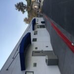 blue awnings for a white building with cars and truck in the background - custom awnings - custom awnings near me - custom awnings for decks - custom awnings for business - custom door awnings near me - spear awnings - aluminum awnings - dome awnings