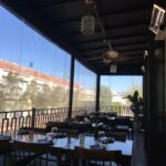 a restaurant with balcony seating with drapes - custom awnings - custom awnings near me - custom awnings for decks - custom awnings for business - custom door awnings near me - spear awnings - aluminum awnings - dome awnings