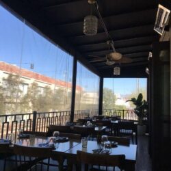 a restaurant with balcony seating with drapes - custom awnings - custom awnings near me - custom awnings for decks - custom awnings for business - custom door awnings near me - spear awnings - aluminum awnings - dome awnings