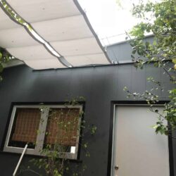small white awnings for a grey house with a white door and a window - standard awnings - concave awnings - aluminum awnings - carports - store front awnings - patio shades