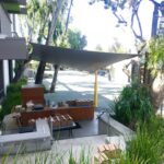 an outdoor store with a white sail shade - custom awnings - custom awnings near me - custom awnings for decks - custom awnings for business - custom door awnings near me - spear awnings - aluminum awnings - dome awnings