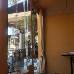 light brown awnings with drapes for a yellow home - custom awnings - custom awnings near me - custom awnings for decks - custom awnings for business - custom door awnings near me - spear awnings - aluminum awnings - dome awnings
