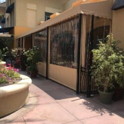 light brown awnings with drapes for a yellow home - custom awnings - custom awnings near me - custom awnings for decks - custom awnings for business - custom door awnings near me - spear awnings - aluminum awnings - dome awnings