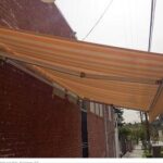 orange house with a yellow stripe awning - custom awnings - custom awnings near me - custom awnings for decks - custom awnings for business - custom door awnings near me - spear awnings - aluminum awnings - dome awnings