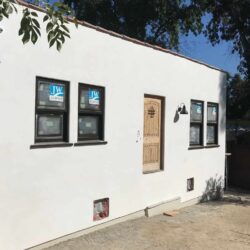 a white house with a wooden door and four windows - custom awnings - custom awnings near me - custom awnings for decks - custom awnings for business - custom door awnings near me - spear awnings - aluminum awnings - dome awnings