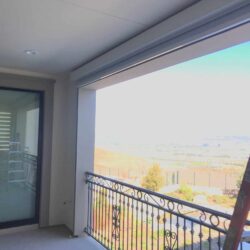 white roller shade for a balcony with a pool in the background - roller shade installation - roller shade ideas - roller shade indoor - roller shade near me - spear awnings - dome awnings - retractable awning company - roller shade cost