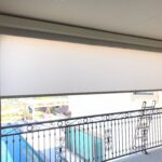 white roller shade for a balcony with a pool in the background - roller shade installation - roller shade ideas - roller shade indoor - roller shade near me - spear awnings - dome awnings - retractable awning company - roller shade cost