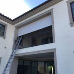 cream house with privacy panel for its second floor balcony - custom awnings - custom awnings near me - custom awnings for decks - custom awnings for business - custom door awnings near me - spear awnings - aluminum awnings - dome awnings