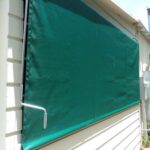 a white house with green privacy panel - custom awnings - custom awnings near me - custom awnings for decks - custom awnings for business - custom door awnings near me - spear awnings - aluminum awnings - dome awnings