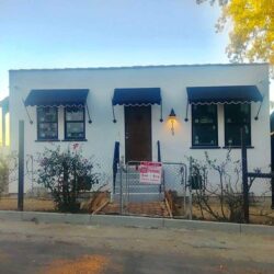 house with gate and blue awnings for door and windows - custom awnings - custom awnings near me - custom awnings for decks - custom awnings for business - custom door awnings near me - spear awnings - aluminum awnings - dome awnings