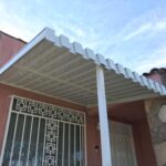 light orange house with white railings and white aluminum awning - custom awnings - custom awnings near me - custom awnings for decks - custom awnings for business - custom door awnings near me - spear awnings - aluminum awnings - dome awnings