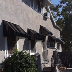 house with black awnings for windows - custom awnings - custom awnings near me - custom awnings for decks - custom awnings for business - custom door awnings near me - spear awnings - aluminum awnings - dome awnings