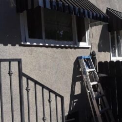 house with black awnings for windows and a dog in front - custom awnings - custom awnings near me - custom awnings for decks - custom awnings for business - custom door awnings near me - spear awnings - aluminum awnings - dome awnings