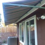 brown house with stripe awning for a window - custom awnings - custom awnings near me - custom awnings for decks - custom awnings for business - custom door awnings near me - spear awnings - aluminum awnings - dome awnings