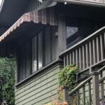 brown stripe awning for a green house covered in plants - custom awnings - custom awnings near me - custom awnings for decks - custom awnings for business - custom door awnings near me - spear awnings - aluminum awnings - dome awnings