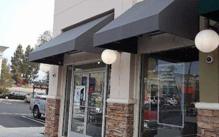 black awnings for a store with cars parked on the side - concave awnings - aluminum awnings - carports - store front awnings - patio shades