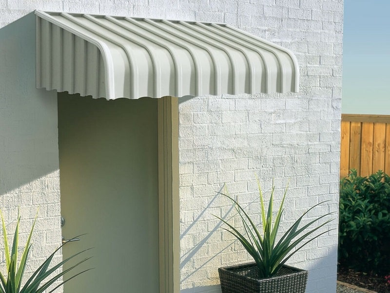 A white aluminum awning over a white patio door and a white wall